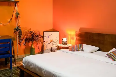 a bedroom with a white bed and an orange wall at Medusa Home Stay in Amman