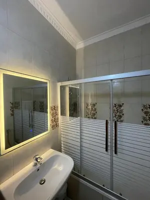 a white bathroom with a sink and a mirror at Shafa Badran Families Apt in Amman