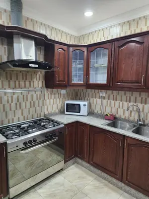 a kitchen with wooden cabinets and a stove and a sink at Shafa Badran Families Apt in Amman