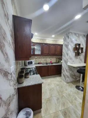 a kitchen with wooden cabinets and a stove top oven at Shafa Badran Families Apt in Amman
