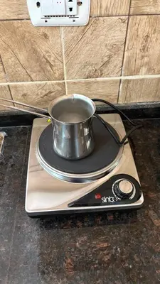 a metal pot sitting on a plate on a counter at Simple home in Madaba