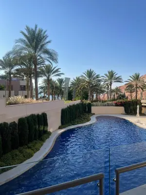 a swimming pool in a resort with palm trees at Alraha VIP Marsa zayed Aqaba in Aqaba