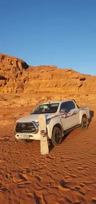 a white suv parked in the desert with a skateboard at Rum Under The Stars Camp in Wadi Rum
