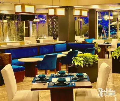a restaurant with blue chairs and tables and a bar at Al Joude Hotel فندق الجود in Irbid