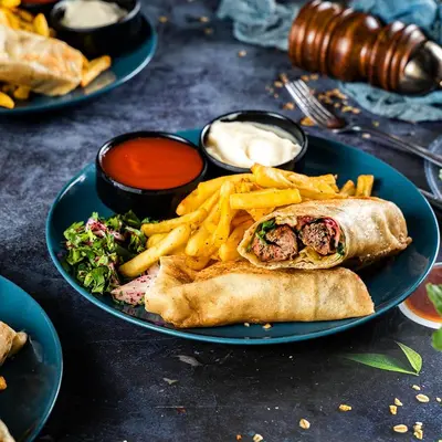 a plate of food with a sandwich and french fries at Al Joude Hotel فندق الجود in Irbid