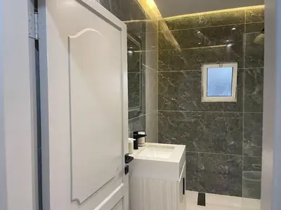 a white bathroom with a sink and a shower at Oqdeh Delux Apartments in Jerash