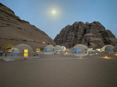 a group of white domes in front of a mountain at Armony rum camp in Wadi Rum