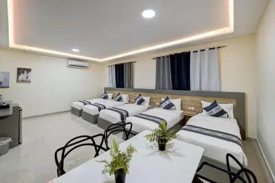 a row of beds in a room with tables and chairs at Three Palms Suites in Aqaba