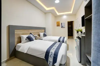 two beds in a hotel room with a kitchen at Three Palms Suites in Aqaba