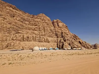 a group of tents in the desert next to a mountain at Sami Al Muzna Rum Camp in Wadi Rum