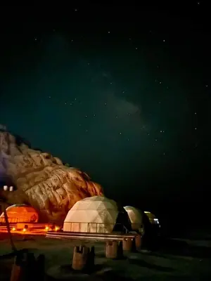 a group of tents in a field at night at Sami Al Muzna Rum Camp in Wadi Rum