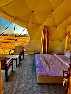 a bedroom in a tent with a bed and a bench at Mirage Camp Wadi Rum in Wadi Rum