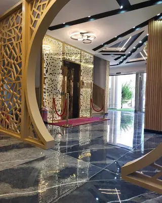 a lobby with a large wall of gold tiles at Pretal Hotel in Al Mafraq