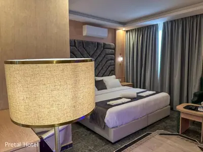 a hotel room with a bed and a lamp at Pretal Hotel in Al Mafraq