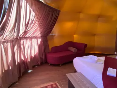 a room with a bed and a red couch at Wadi Rum Spring Moon & Jeep Tour in Wadi Rum
