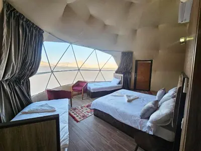 a room with two beds and a large window at Wadi Rum Spring Moon & Jeep Tour in Wadi Rum