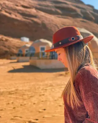 a woman wearing a hat standing in the desert at Sun Luxury Rum Camp in Wadi Rum