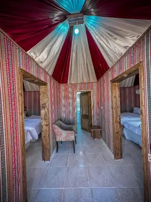 a tent with two beds and a chair in a room at Sun Luxury Rum Camp in Wadi Rum