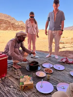 a group of people standing around a table with food at Talal Wadi Rum in Wadi Rum