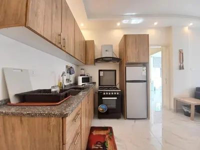 a kitchen with wooden cabinets and a black refrigerator at Shmeisani homes central location near Abdali in Amman