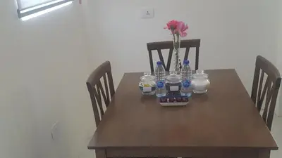 a wooden table with a vase of flowers and bottles on it at Shmeisani homes central location near Abdali in Amman