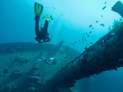 a person swimming in the ocean next to a wreck at Friends Oasis in Aqaba
