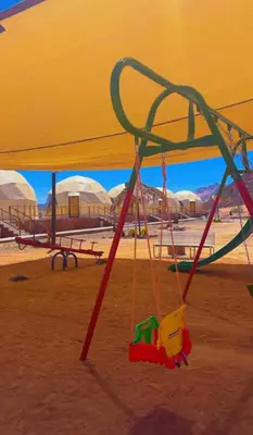 a swing set in a playground with a yellow umbrella at Bilal luxury camp in Wadi Rum