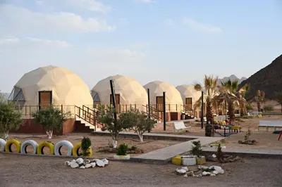 a group of domed buildings with trees and palm trees at Bilal luxury camp in Wadi Rum