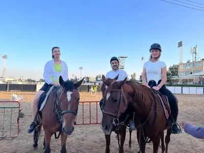 three women are sitting on horses in front of a fence at بيت جرش - Jerash House in Jerash