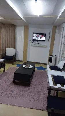a living room with a table and a tv on a wall at Mount lareen cottage كوخ جبل لارين in Ajloun
