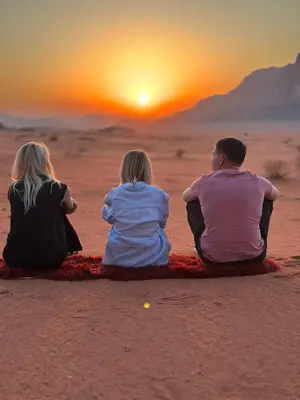 three people sitting in the desert watching the sunset at Milk way desert in Wadi Rum