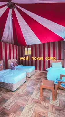 two beds in a room with a red tent at wadi novas camp in Wadi Rum