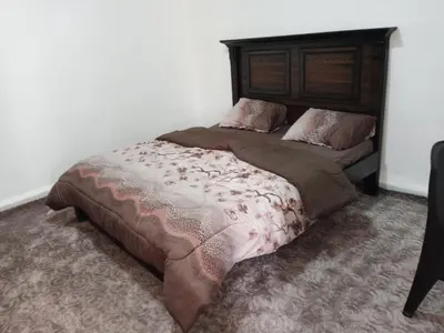 a bedroom with a large bed with a wooden headboard at petra sun apartment in Wadi Musa