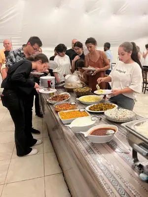 a group of people standing around a buffet table with food at Wadi Rum Rose Luxury camp in Wadi Rum