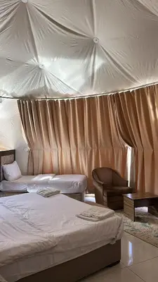 a bedroom with two beds and a chair at Sidra Luxury Camp in Rum in Wadi Rum