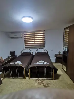 a bedroom with two beds and a desk and windows at Beit Al Hasan بيت الحسن in Um Qeis