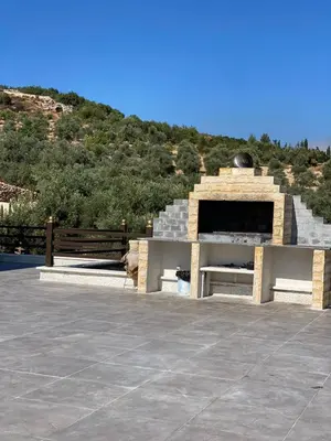 a stone fireplace with a bench in front of a hill at Souf view in Jerash