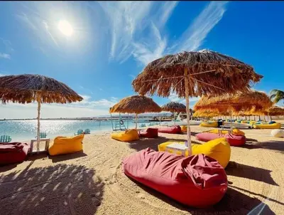 a beach with many chairs and umbrellas and the ocean at ِAfnan hotel in Aqaba