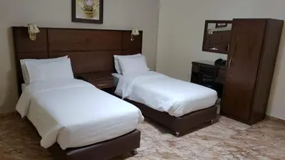 two beds in a hotel room with white sheets at Karam Inn in Aqaba