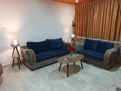 a living room with two blue couches and a table at Suad Apartment in Amman