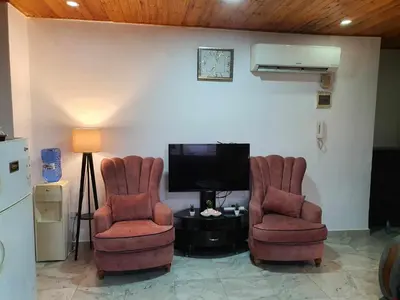 a living room with two chairs and a television at Suad Apartment in Amman