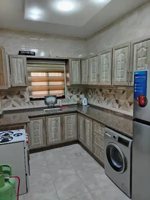 a kitchen with wooden cabinets and a washer and dryer at شقة فاخرة مع مطل luxerious with nice view in Amman