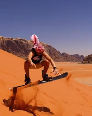 a man sitting on a snowboard in the desert at Wadirum winter in Wadi Rum