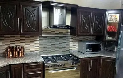 a kitchen with wooden cabinets and a stove and a microwave at شقق المومني in Amman
