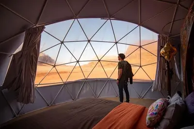 a man standing in a tent looking out of a window at Golden Gate Luxury Camp in Wadi Rum