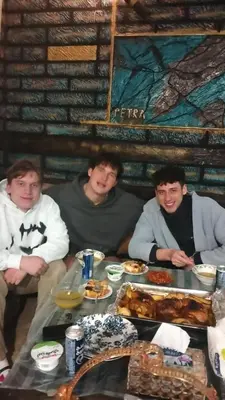 a group of three men sitting around a table with food at Petra Anas House in Wadi Musa
