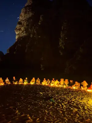 a group of people sitting on the beach at night at wadi rum tha moon in Wadi Rum