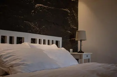 a bedroom with a white bed with a stone wall at Saraya locanda in Al Salt
