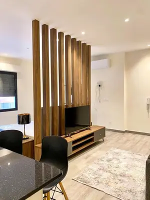 a living room with a tv and a table and chairs at Odeh Residence in Aqaba
