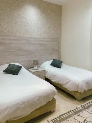 a bedroom with two beds and a table with a lamp at Odeh Residence in Aqaba